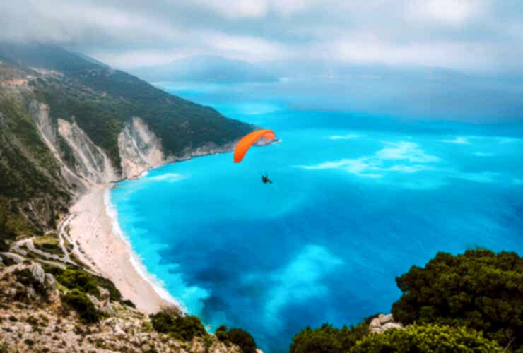 Aerial view of the paraglider flying over gorgeous Myrtos beach. Amazing water colors and beautiful coastline on kefalonia island, Greece